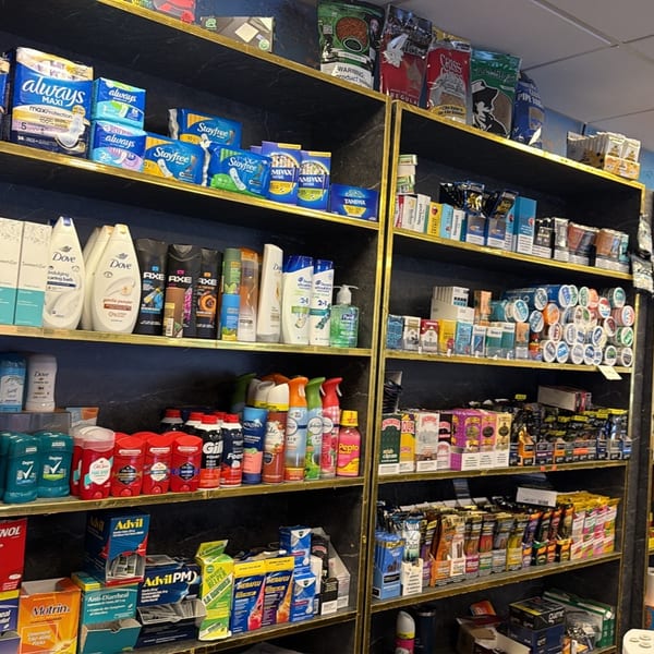 Shelves in a convenience store filled with various personal care products, medications, and tobacco items.